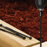 This image depicts a FastenMaster TimberLOK screw being screwed into a piece of wood.