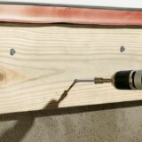 This image depicts a wood screw from FastenMaster being drilled into a piece of wood.