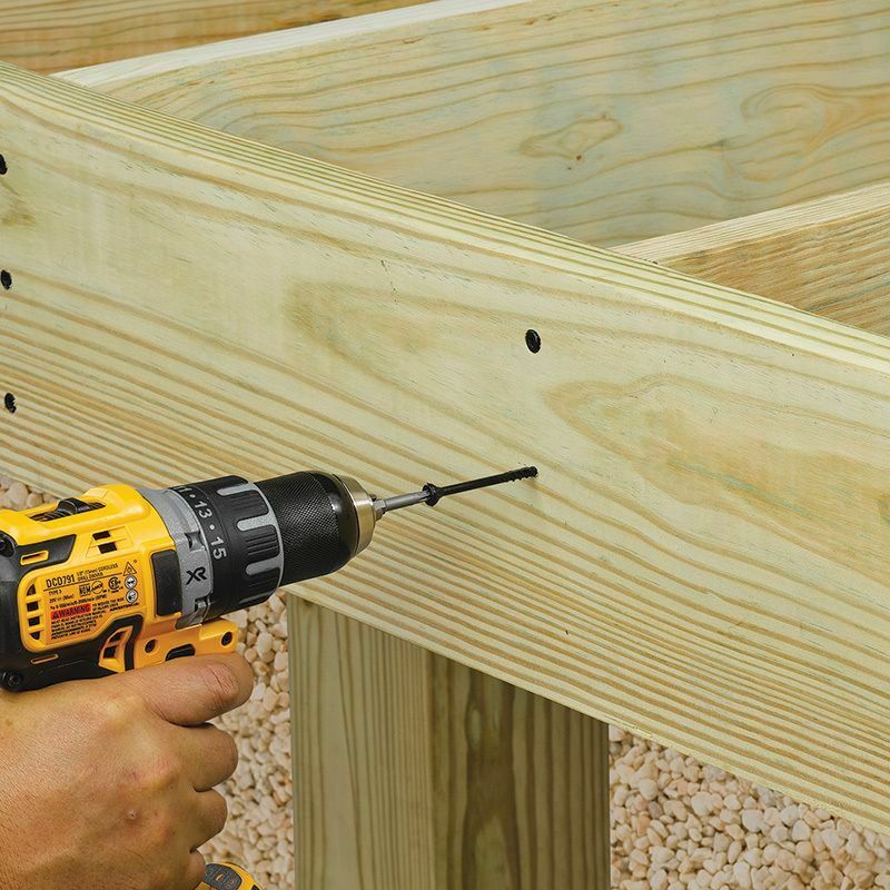 This image depicts a screw being drilled into a piece of wood decking.