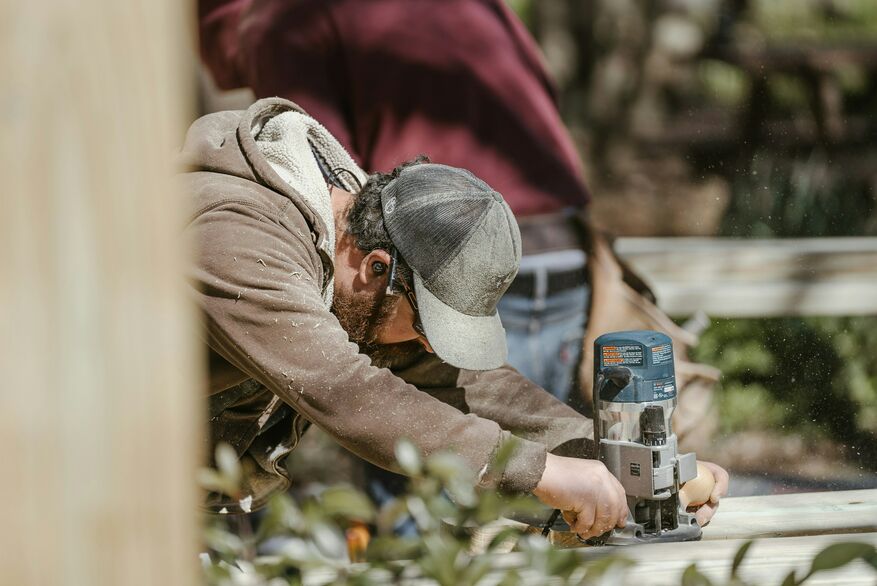 A professional operates a handheld power tool for a deck project.