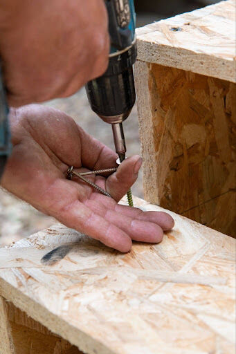 A construction worker is using a hand-driving method to install screws on a job site.