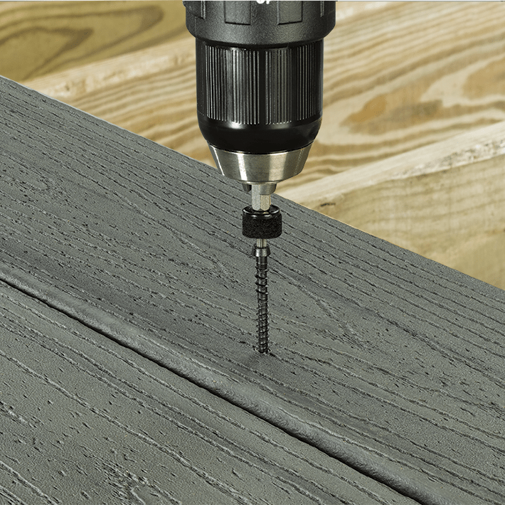 This image depicts a screw being drilled into a piece of composite decking.